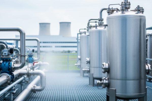 “Stainless-steel water recycling tanks and membrane modules in an industrial facility with clean pipes under bright overcast light.”